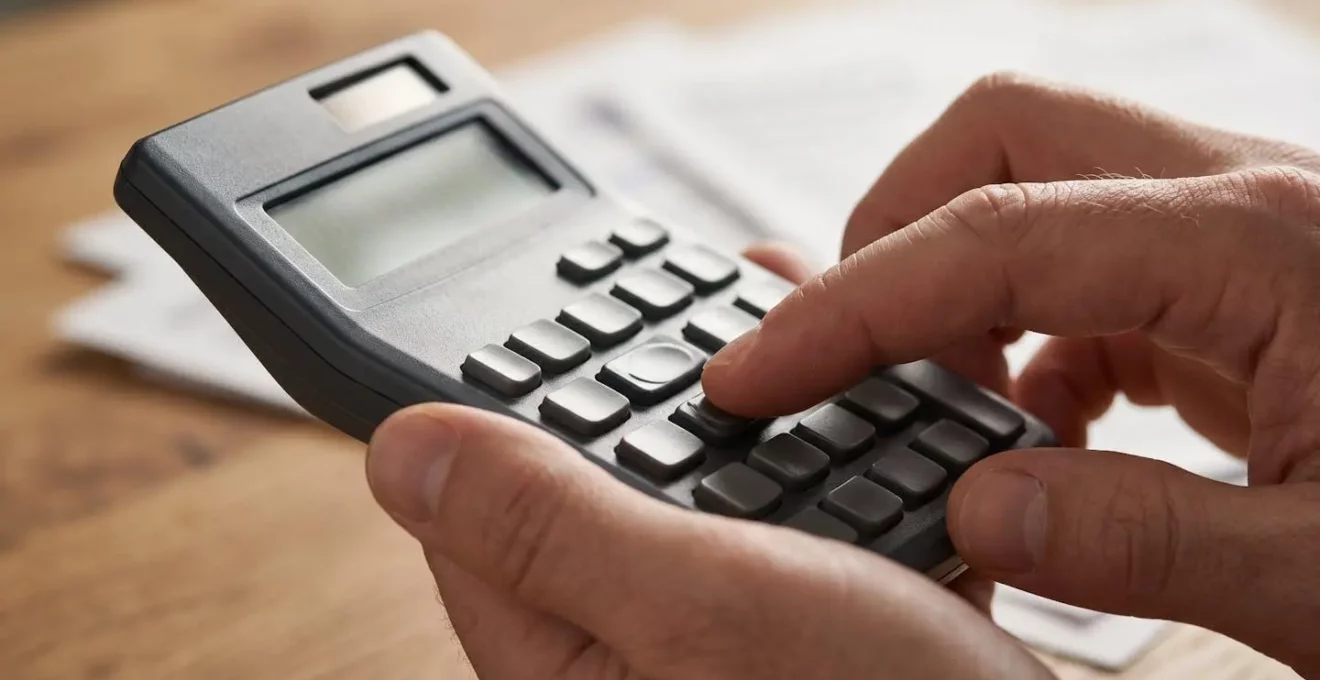 Mains utilisant une calculatrice avec des documents d'assurance flous en arrière-plan